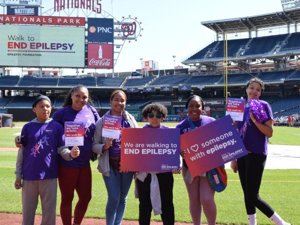 A group of Walk participants smiling and holding signs at home plate.